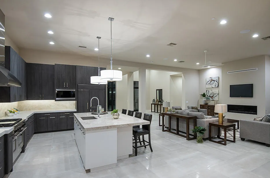 Modern open-plan kitchen and living area with dark cabinetry, marble island and recessed lighting